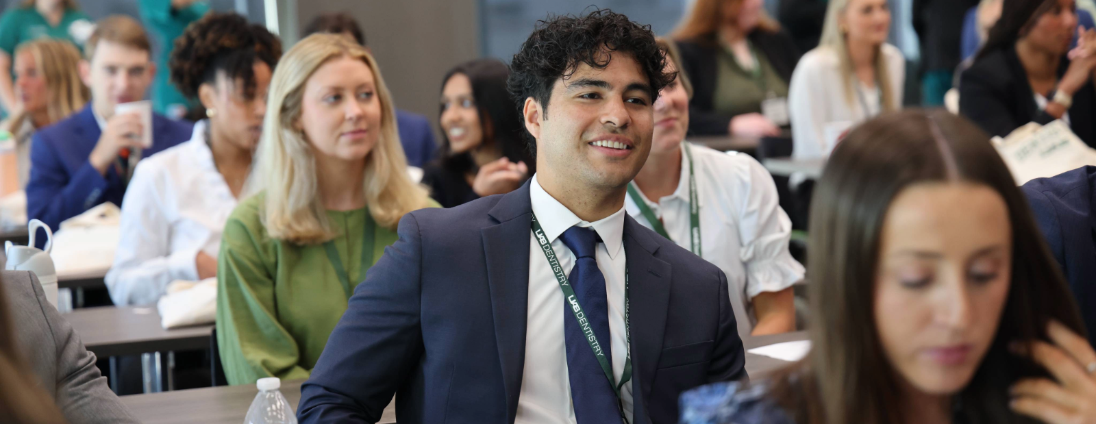 Man wearing lanyard reading "UAB Dentistry" among others in a conference setting