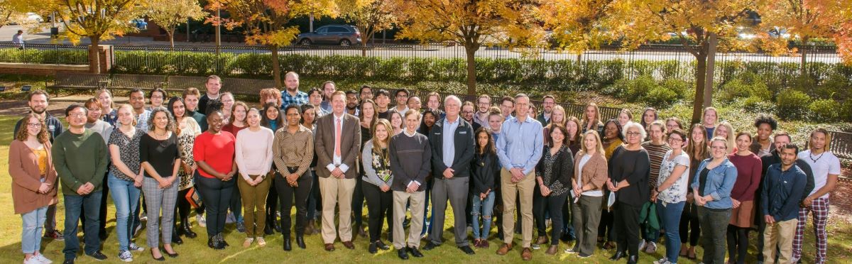 Large group of CNET-affiliated faculty and staff posing outside, trees with yellow leaves in background.