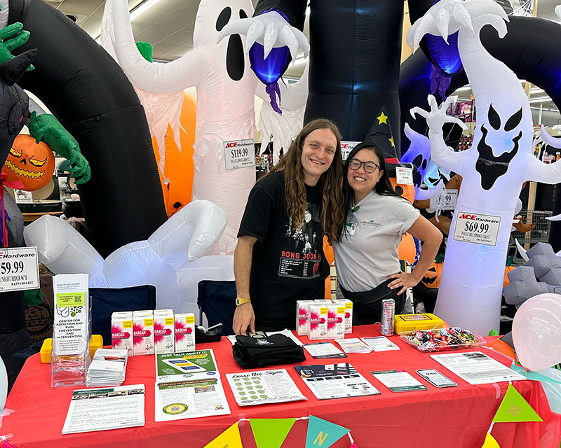 Volunteers at a table in front of inflatable halloween ghosts. 