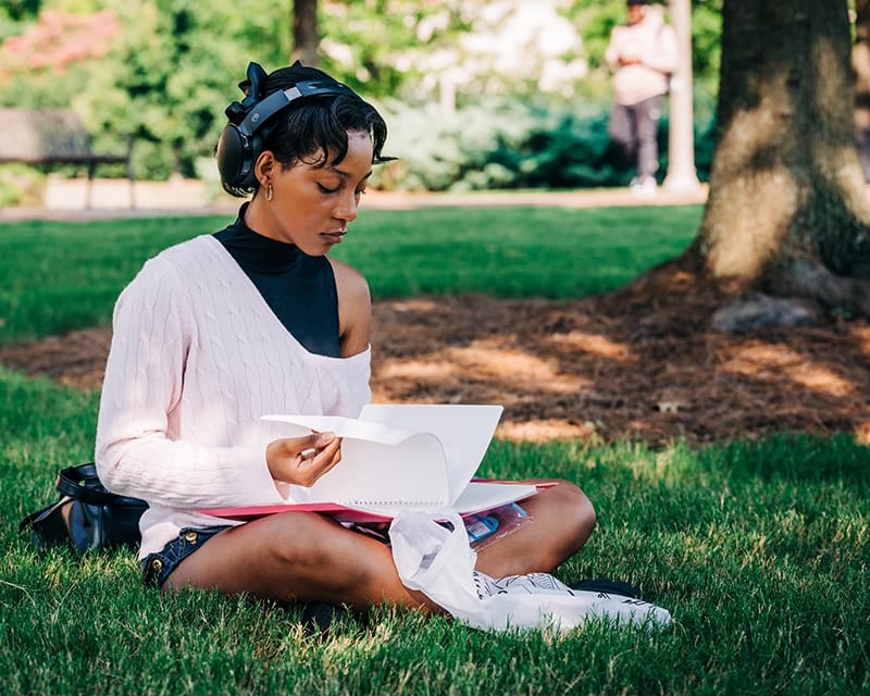 Student studying on campus green.