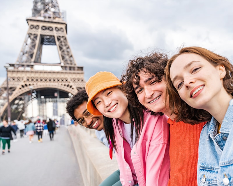 Students smiling in front of the Eifel Tower. 