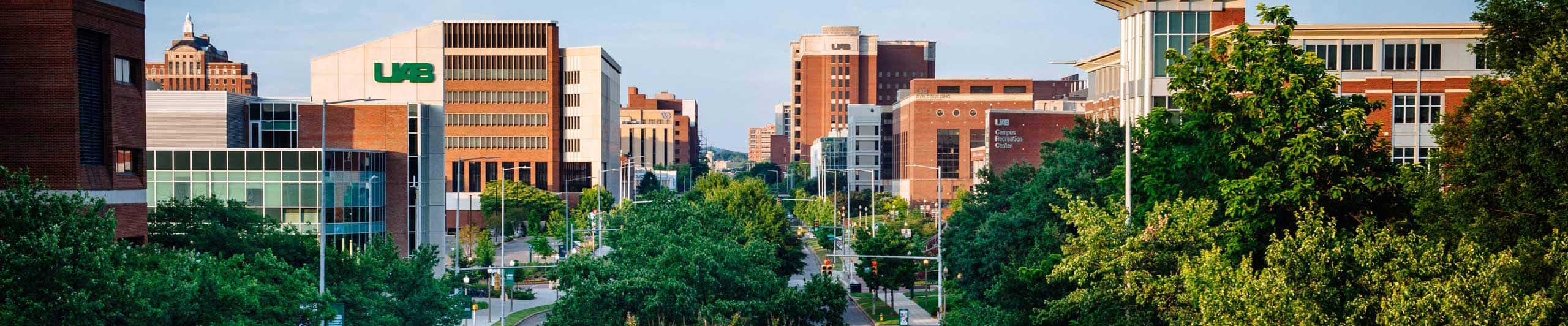 Drone style shot down University Boulevard showing large brick university buildings with UAB logos.