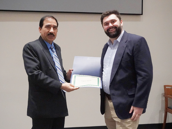 Dr. Javed handing Logan Stone his award at Scholars Symposium 2024