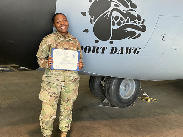 Barganier, dressed in full cammo, holds degree in front of plane. 