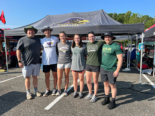 A group of participants pose with arms aorund each other outside an event tent. 