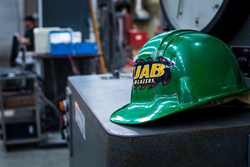 A green hard hat with a UAB Blazers sticker. 