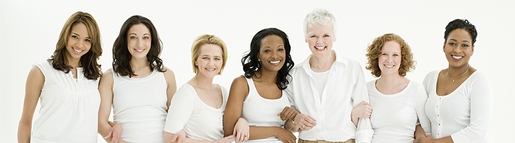 A group of smiling, confident women of various ages and ethnicities standing together in white shirts.