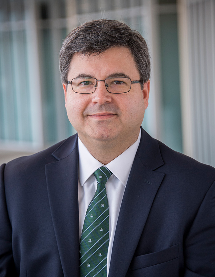 Headshot of Bradley Barnes in a black blazer and green tie. 