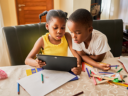 Cropped shot of two young siblings using a digital tablet while sitting at home