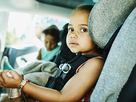 Portrait of young girl sitting in car seat before family road trip