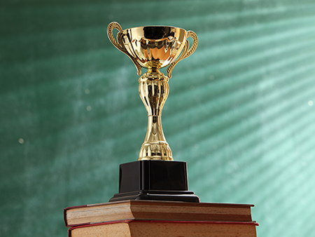 trophy on top stack of book in front of black board