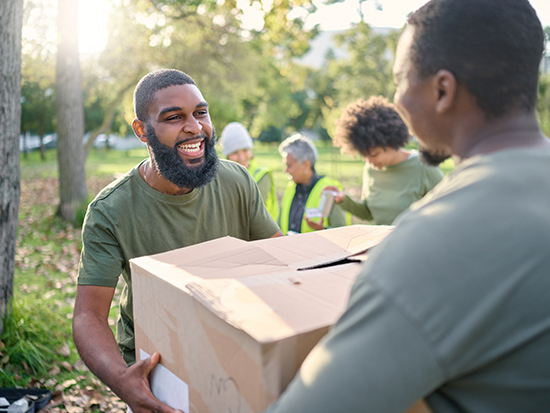 Man in park volunteering and holding a box full of donations.