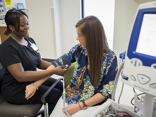A member of a UAB health care team adjust a blood pressure cuff on a patient in this staged photo