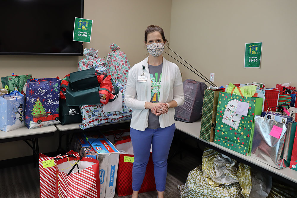 Meredith Kahl, director of Off-Campus Student and Family Engagement, standing amongst a pile of donated presents