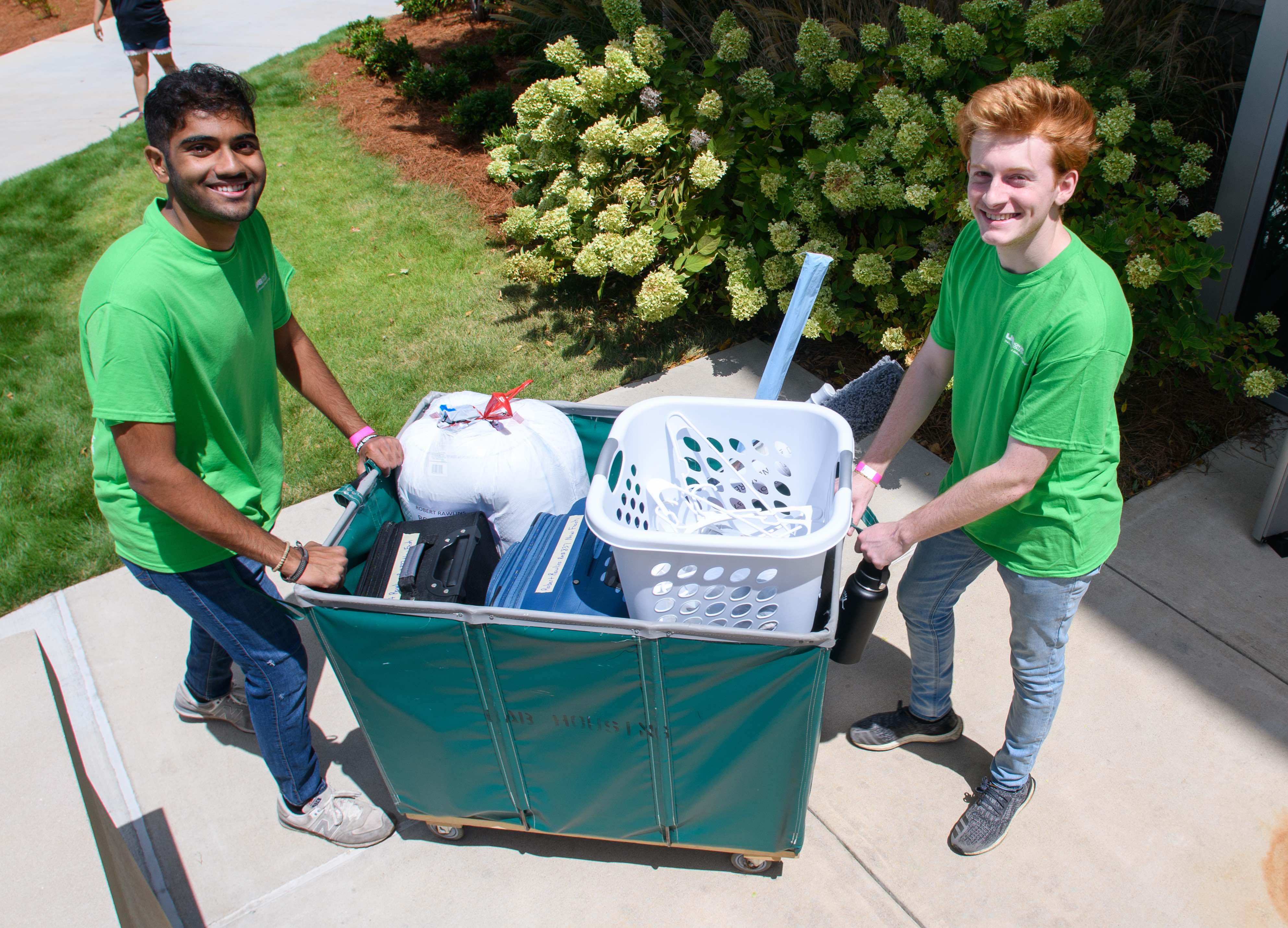 2019 UAB Honors College Move-In Day. Two smiling student volunteers are pushing a moving cart on a sidewalk on August 21, 2019.