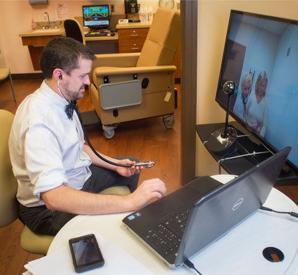 Eric Wallace examines a patient using telehealth technology