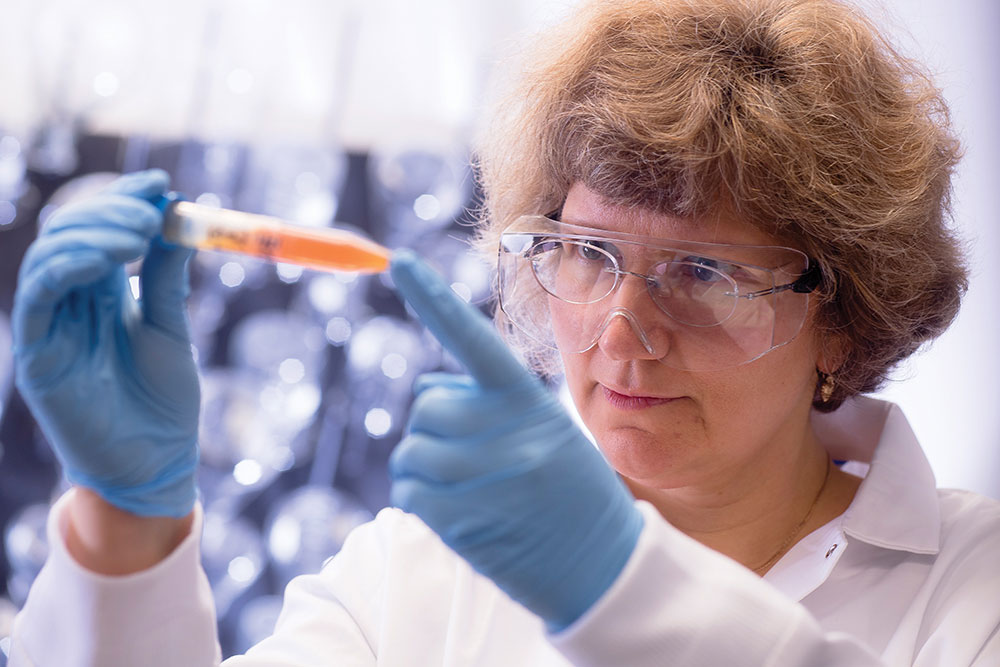 Photo of Eugenia Kharlampieva in lab looking at orange solution in tube