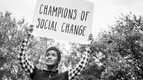 Photo of Ajanet Rountree holding up sign with headline: Champions of Social Change
